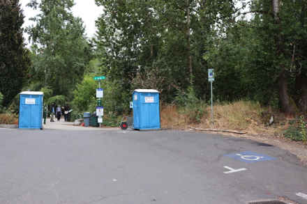 Accessible parking space – two porta potties – bike rack – park rules – dog bags and trash can at park entrance